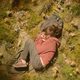 Bella Ramsey as Ellie sleeps curled up in a grassy space in HBO's The Last of Us.